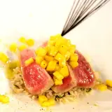 Röda skivor av tonfisk med tärnad mango ovanpå, serverade på ris. En utsökt kombination av tonfisk och mango.