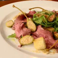 En tallrik med tunt skivad rostbiff, kapris, ruccola och krutonger. En klassisk vitello tonnato-inspirerad rätt.