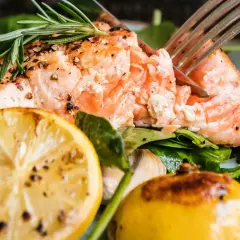 En saftig bit lax, perfekt stekt i stekpanna, serveras med citron, körsbärstomater och färska örter.