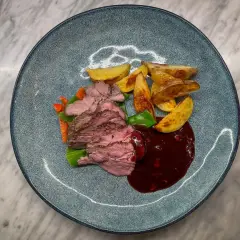 Skivad lammrostbiff med rostade potatisklyftor, grönsaker och en mörk sås. Ett perfekt lammrostbiff recept för en festmåltid.