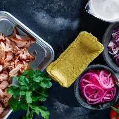 Förberedelser för lax tacos: saftig lax, majstortillas, rödlök, rödkål, koriander och tomater.