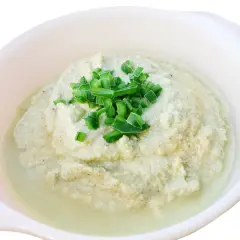 Krämig baba ganoush toppad med färsk gräslök i en vit skål.