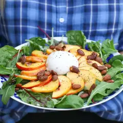 En somrig sallad med skivad persika, krämig burrata, mandlar och gröna blad. En perfekt kombination av sött och salt.