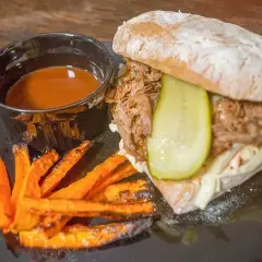 En saftig pulled pork-macka med krispiga sötpotatispommes och en skål med härlig sås till pulled pork.