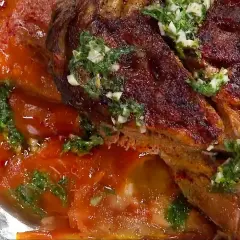 En saftig lammbog, perfekt för ett härligt lammbog recept, serverad med en smakrik tomatsås och färska örter.