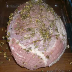 Rå skinkstek med kapris och peppar, redo för ugnen. Viktigt att ha koll på skinkstek temperatur för perfekt resultat.