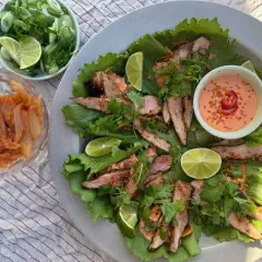 Grillad fläskkarré i salladsblad med kimchi, lime och en krämig sås. Ett perfekt pluma recept för en lätt och smakrik måltid.