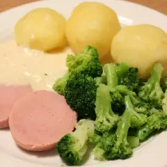 En tallrik med kokt falukorv med pepparrotssås, potatis och broccoli. En klassisk svensk middag.