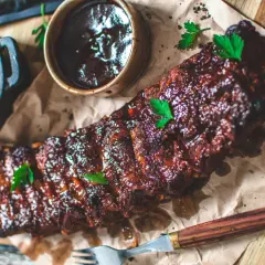Saftiga spareribs i ugn, glaserade och serverade med en skål coleslaw och BBQ-sås. Perfekt för en härlig middag.