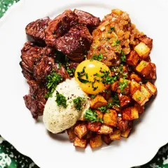En tallrik med saftig biff, krispiga potatisbitar, en äggula och en klick sås. Ett spännande njurtapp recept att prova!