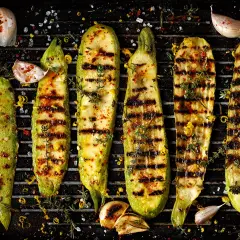 Grillad zucchini med vitlök, örter och citronzest på en grillpanna. Perfekt tillbehör för sommaren.