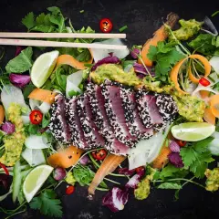 Halstrad tonfisk med sesamfrön, serverad med en fräsch sallad av grönsaker, lime och avokado. Ett perfekt halstrad tonfisk recept för en lätt lunch.