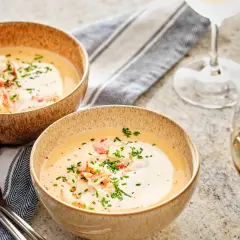 Två skålar med krämig hummersoppa, toppad med hummerkött och gräslök. Perfekt för ett hummersoppa recept.