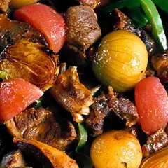 En mustig lammgryta med ben, full av möra köttbitar, gyllene lök, tomater och gröna paprikastrimlor.