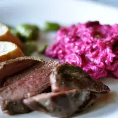 Skivad lammrostbiff med perfekt innertemp, serverad med rödbetssallad och bröd.