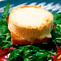 Varm chevre på rostat bröd med gröna blad och röda inslag. Ett enkelt och gott chevre recept.