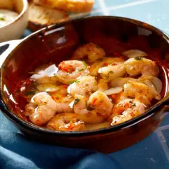 En skål med saftiga gambas pil pil, fulla av vitlök och chili, redo att avnjutas med rostat bröd.