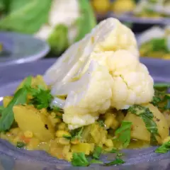 En tallrik med en läcker gryta där man kan koka blomkål med potatis och linser, garnerad med färsk persilja.