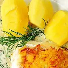 En portion med kokt potatis, en bit stekt fisk och en generös klick varm dillsås. Garnerat med färsk dill och en citronskiva.