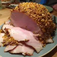 En saftig julskinka med en härlig griljering av nötter och ströbröd, redo att serveras.