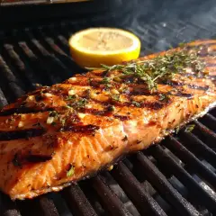 En saftig bit grillad fisk med citron och örter på grillen.