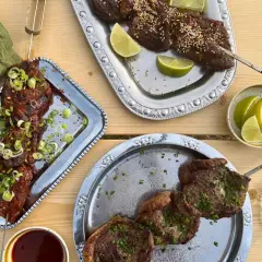 Grillad köttspett med lime och sesamfrön. En skål med sås och en grön duk. Sommarens smaker, som svart trumpetsvamp sås.