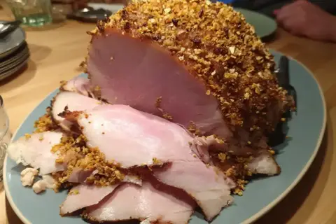 En saftig julskinka med en härlig griljering av nötter och ströbröd, redo att serveras.