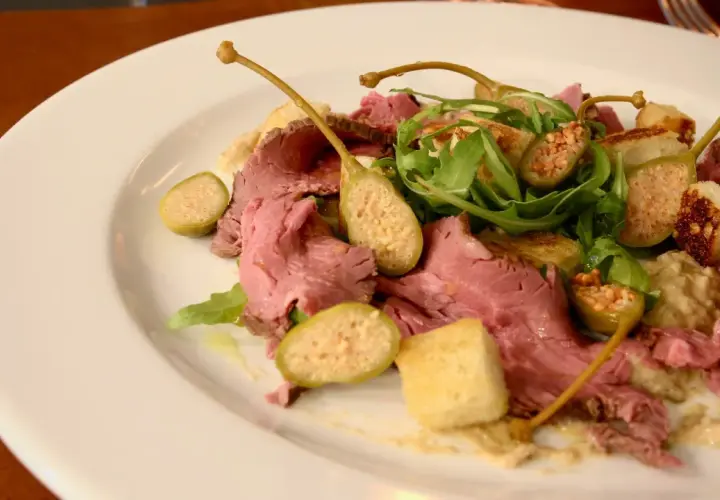 En tallrik med tunt skivad rostbiff, kapris, ruccola och krutonger. En klassisk vitello tonnato-inspirerad rätt.