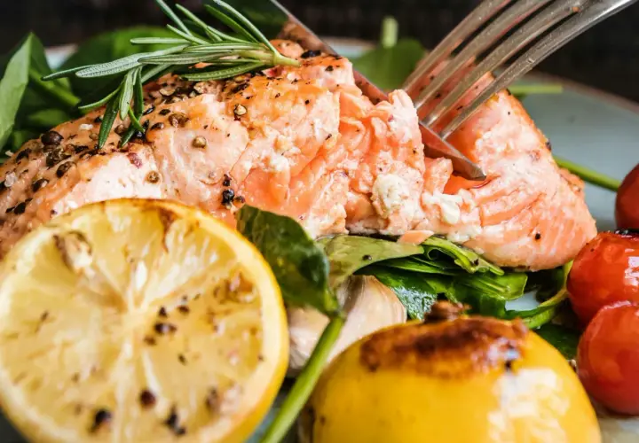 En saftig bit lax, perfekt stekt i stekpanna, serveras med citron, körsbärstomater och färska örter.