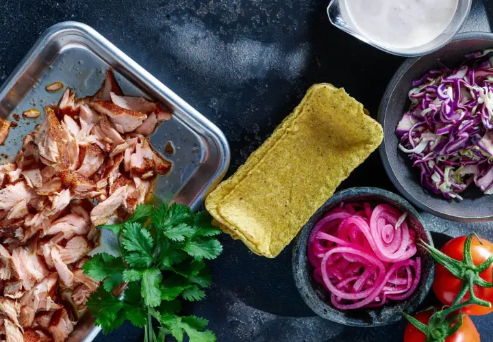 Förberedelser för lax tacos: saftig lax, majstortillas, rödlök, rödkål, koriander och tomater.