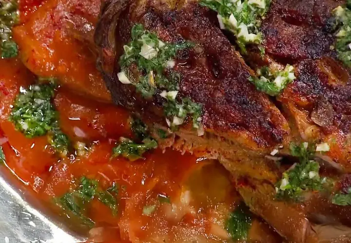 En saftig lammbog, perfekt för ett härligt lammbog recept, serverad med en smakrik tomatsås och färska örter.