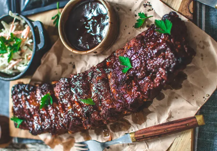 Saftiga spareribs i ugn, glaserade och serverade med en skål coleslaw och BBQ-sås. Perfekt för en härlig middag.