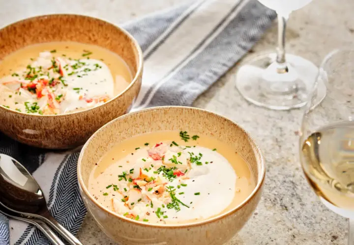 Två skålar med krämig hummersoppa, toppad med hummerkött och gräslök. Perfekt för ett hummersoppa recept.