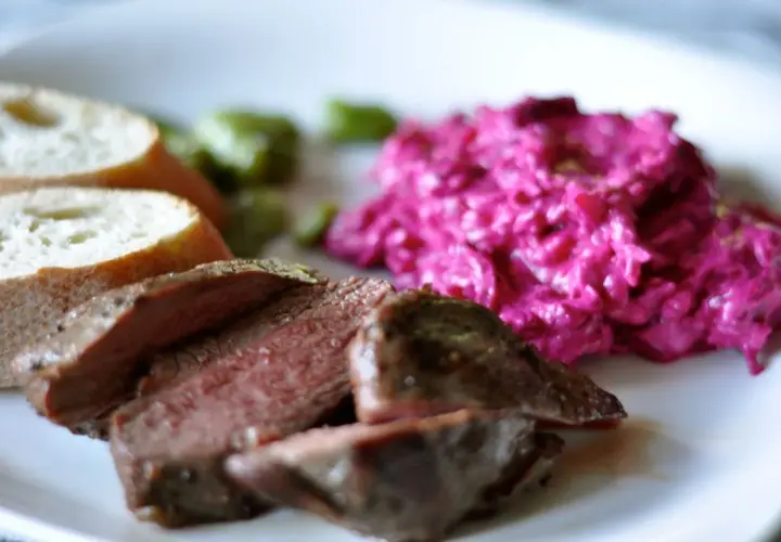 Skivad lammrostbiff med perfekt innertemp, serverad med rödbetssallad och bröd.