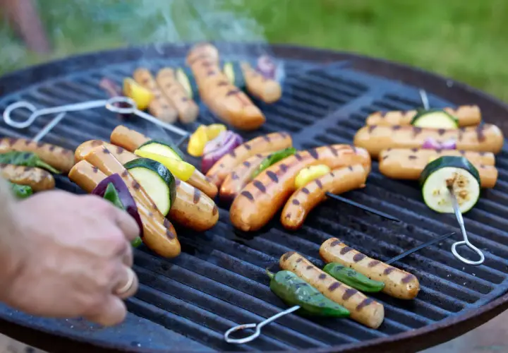 Grilla korv med grönsaker på en kolgrill. Röken stiger och ger en härlig doft.