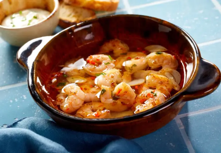 En skål med saftiga gambas pil pil, fulla av vitlök och chili, redo att avnjutas med rostat bröd.