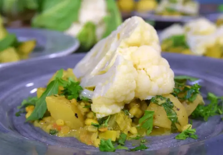 En tallrik med en läcker gryta där man kan koka blomkål med potatis och linser, garnerad med färsk persilja.