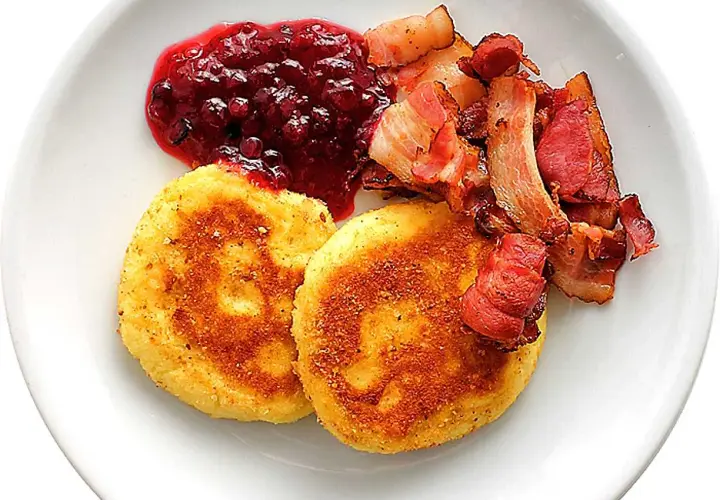 Två gyllene potatisbullar airfryer serveras med rårörda lingon och knaperstekt bacon.