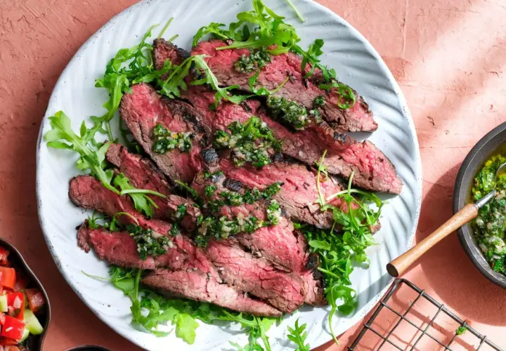 Skivad flapsteak med chimichurri och ruccola, perfekt för ett snabbt och smakrikt flapsteak recept. Serveras med en fräsch tomatsallad.