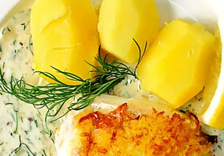 En portion med kokt potatis, en bit stekt fisk och en generös klick varm dillsås. Garnerat med färsk dill och en citronskiva.