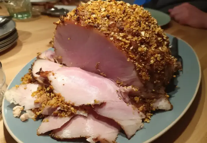 En saftig julskinka med en härlig griljering av nötter och ströbröd, redo att serveras.
