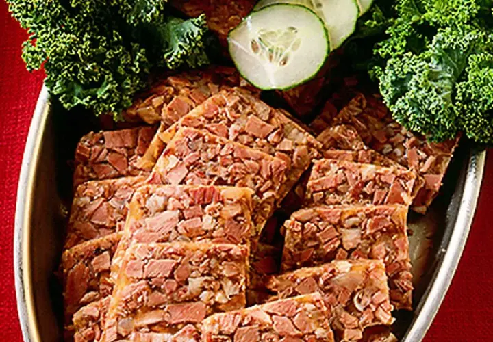 Skivor av kalvsylta, garnerat med grönkål och gurka. Ett klassiskt kalvsylta recept som passar perfekt på julbordet.