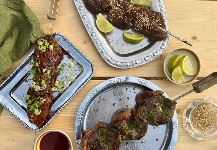 Grillad köttspett med lime och sesamfrön. En skål med sås och en grön duk. Sommarens smaker, som svart trumpetsvamp sås.