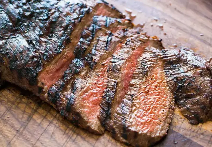 Skivad, grillad flankstek med vackra grillränder och en härlig röd kärna, redo att serveras med chimichurri.