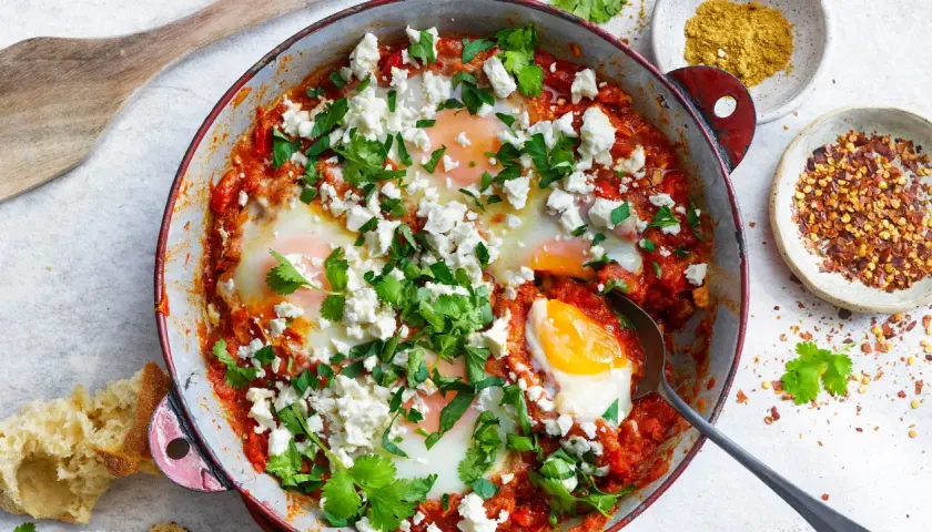 En härlig shakshuka med ägg i tomatsås, toppad med fetaost och koriander. Perfekt för ett smakrikt shakshuka recept.