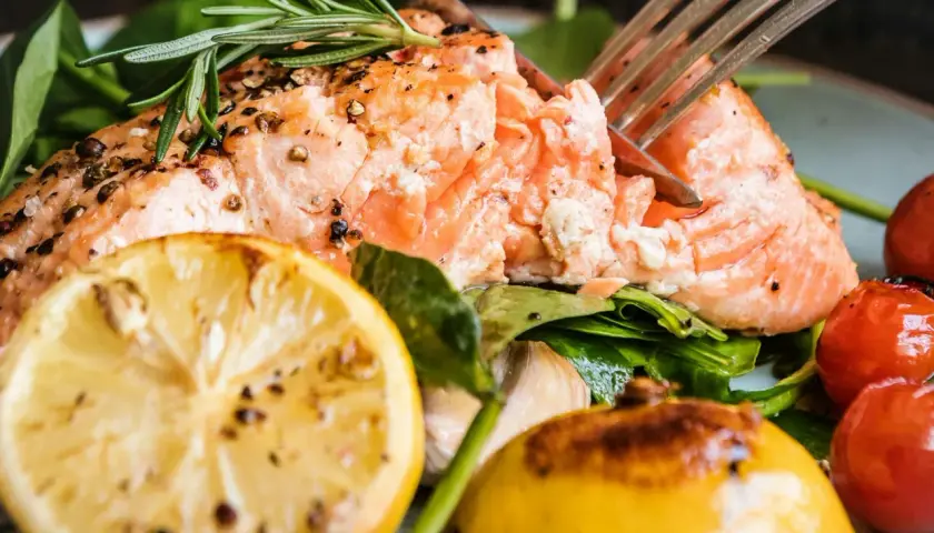 En saftig bit lax, perfekt stekt i stekpanna, serveras med citron, körsbärstomater och färska örter.