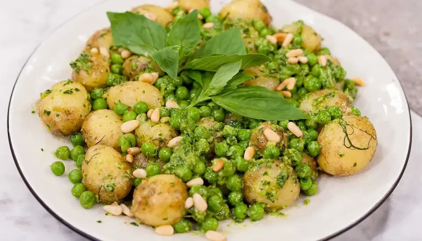 En härlig pesto potatis med gröna ärtor och pinjenötter, toppad med färsk basilika.