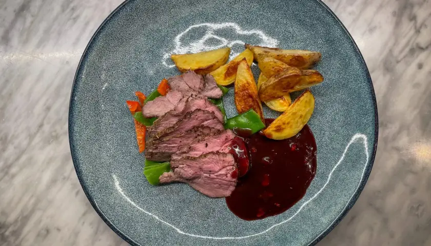 Skivad lammrostbiff med rostade potatisklyftor, grönsaker och en mörk sås. Ett perfekt lammrostbiff recept för en festmåltid.