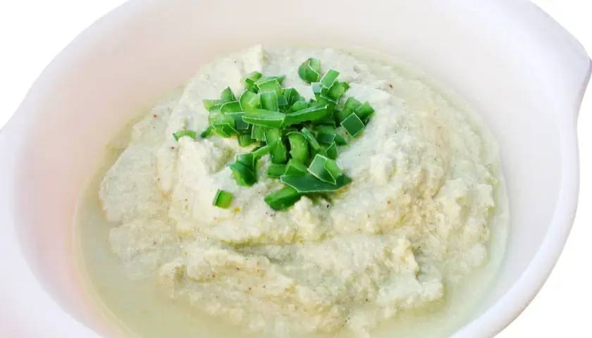 Krämig baba ganoush toppad med färsk gräslök i en vit skål.