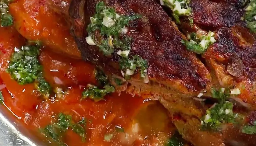 En saftig lammbog, perfekt för ett härligt lammbog recept, serverad med en smakrik tomatsås och färska örter.